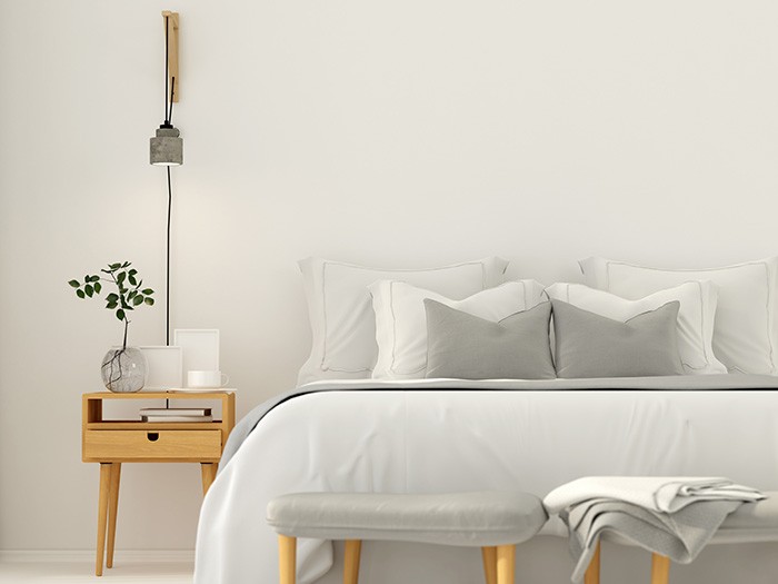 White linen upholstered bed with a modern natural wood bedside table 